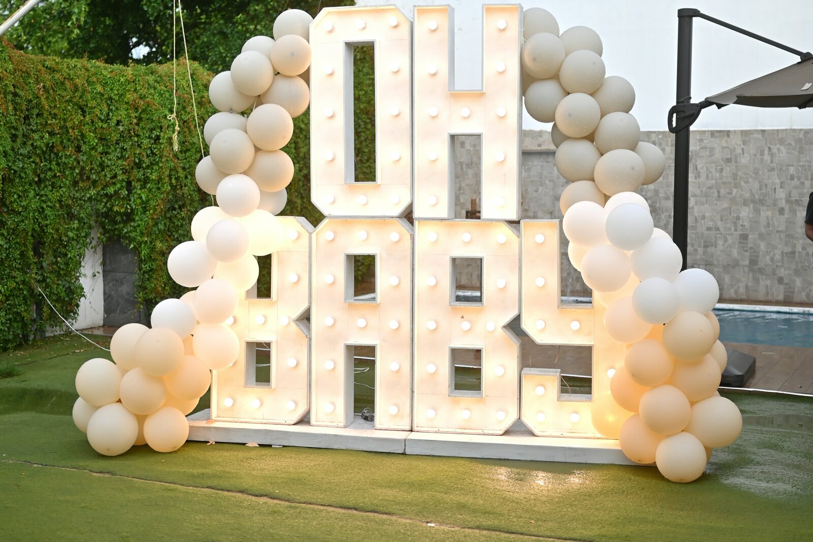 Oh Baby light-up sign with neutral balloons at a baby shower